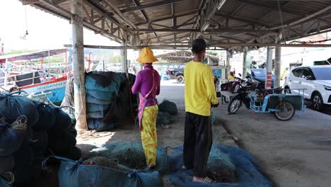 two people untangling fishing nets at a harbor