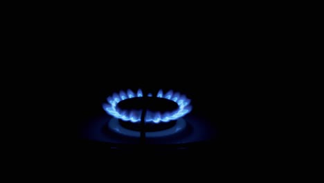 gas burner on, glowing with blue flame, at night in kitchen. close-up