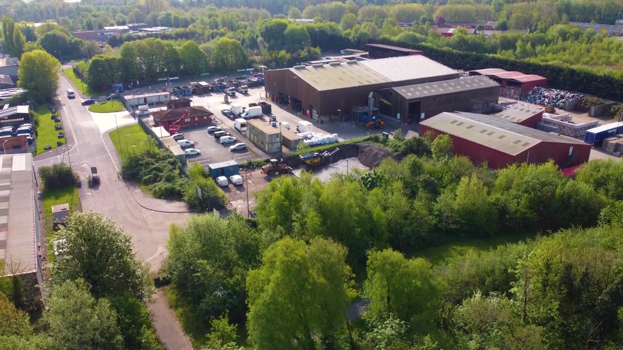 Stigende luftfoto af moderne genbrugscenter og grøn sorteringsanlæg. Bæredygtig affaldshåndtering med lagre, der opbevarer råmaterialer. Industriel genanvendelse. 4K.