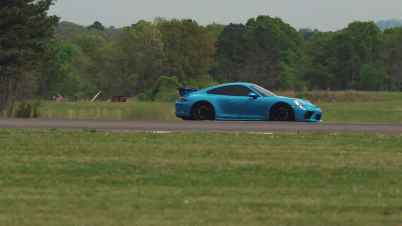 Un'auto sportiva blu sfreccia velocemente lungo una pista d'asfalto all'aperto