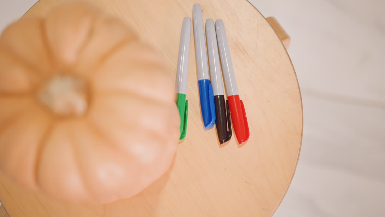 Preparación de manualidades de otoño. Escena con rotuladores coloridos y calabazas. Vista cenital que muestra rotuladores vibrantes y detalles de calabazas. Imagen de estudio en tonos cálidos de rotuladores y calabaza en miniatura sobre superficie de madera.