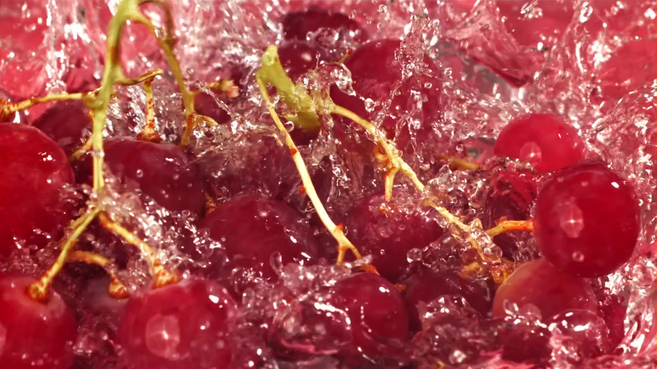 Uva rossa che si tuffa nell'acqua rossa al rallentatore