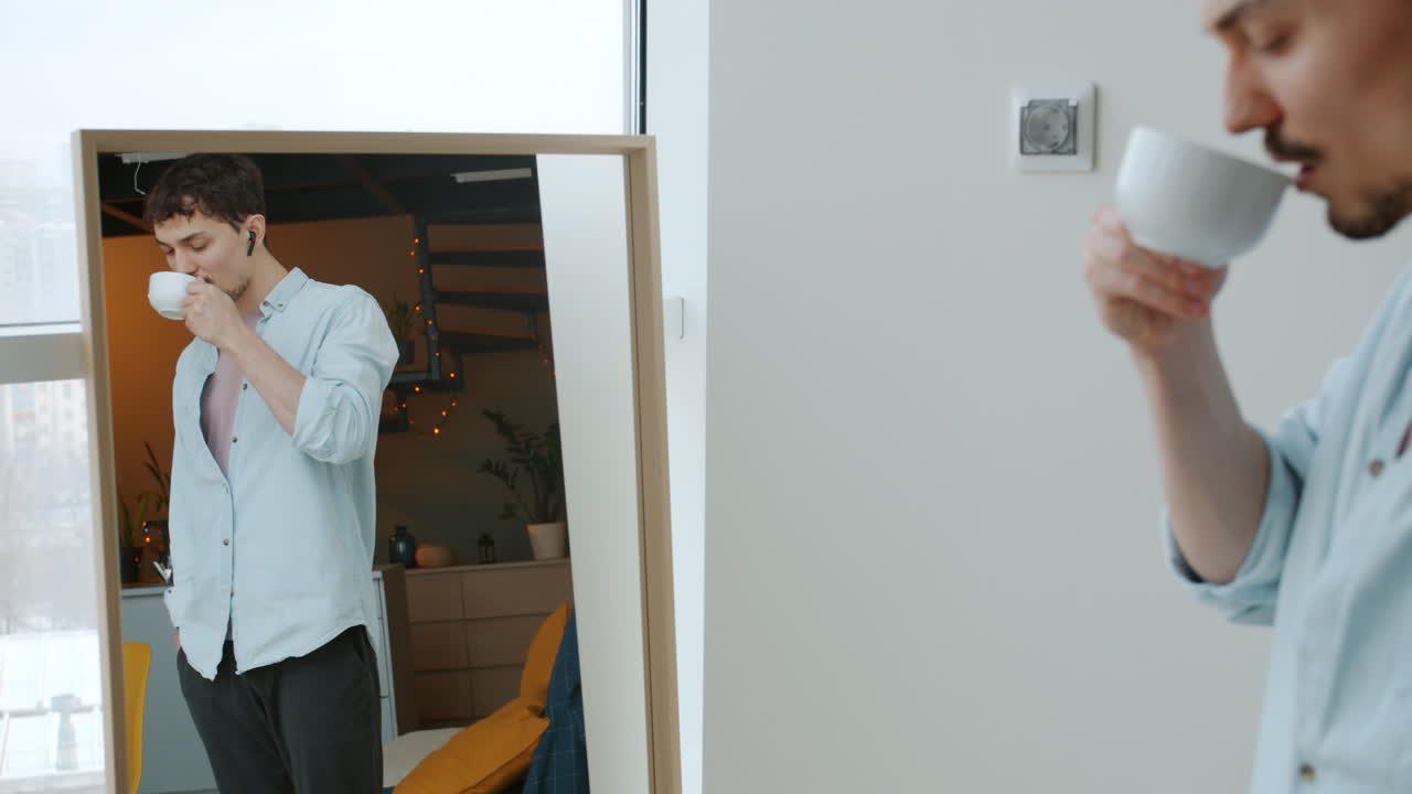 Man drinking coffee in front of a mirror