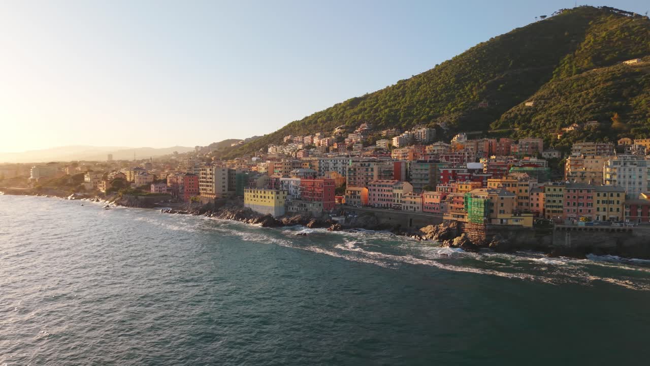 Golden hour aerial view of coastal city with colorful buildings and calm sea