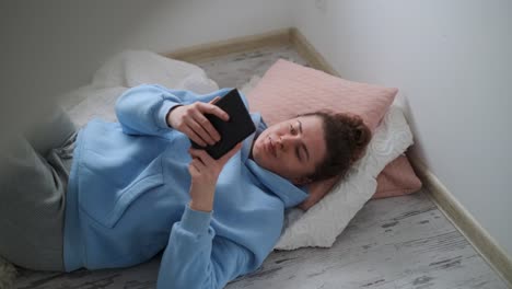woman relaxing on the floor, using a smartphone