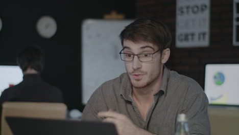 Cheerful-business-man-talking-by-video-chat-in-dark-office.