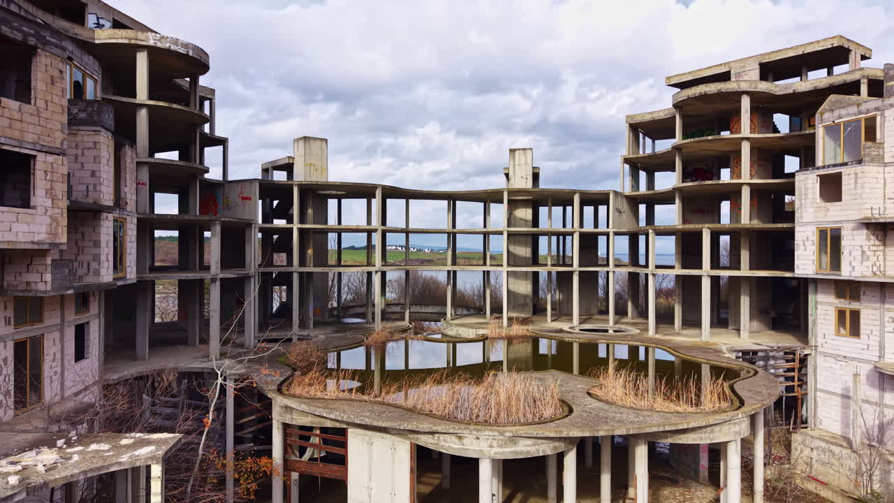 Abandoned architectural marvel standing amid nature's reclaiming force in a tranquil landscape near water