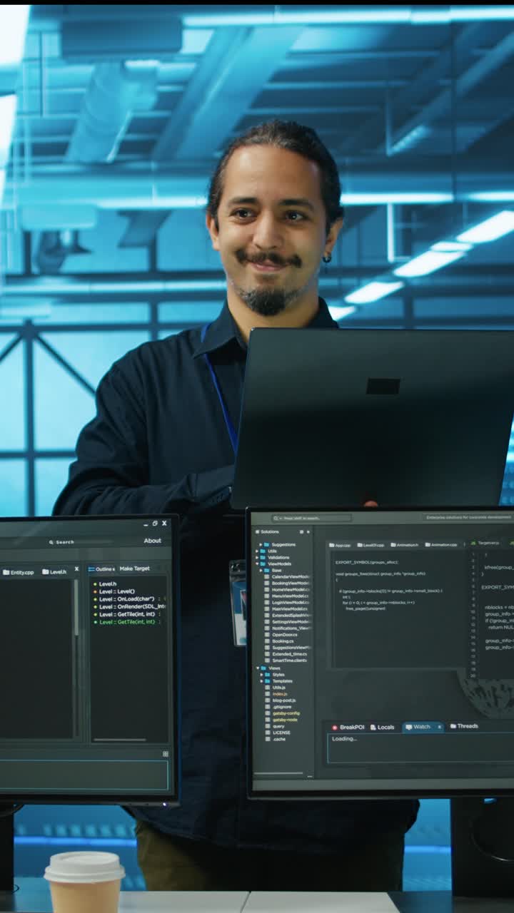Male Developer Working on Laptop and Multiple Screens in Tech Office