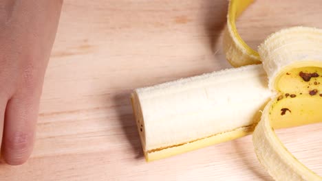 a hand peels a banana on a table