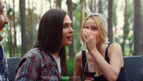 young women sharing secrets on backyard. girls chatting on party outdoors