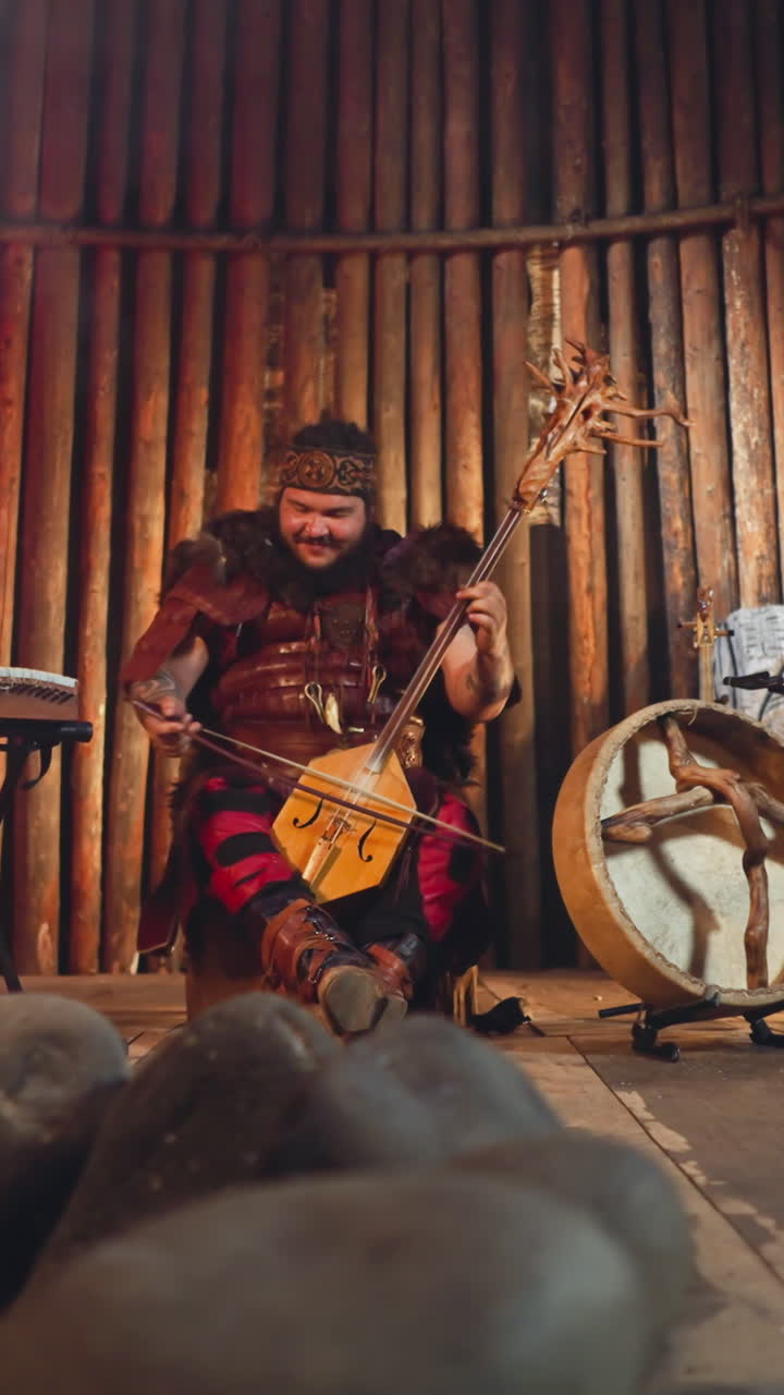 Folk rock band plays traditional Altai music with ancient instruments near stone statue in ail house. Emotional integration of old culture in modern life