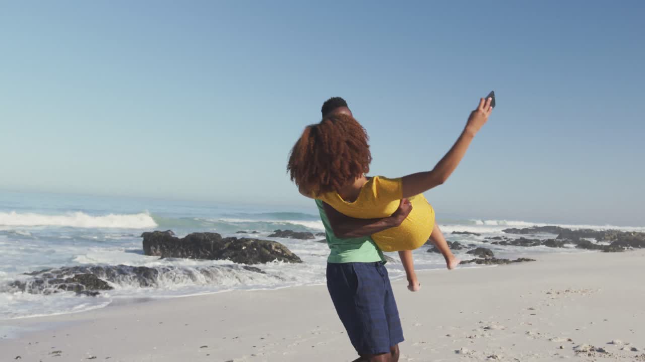 una pareja afroamericana tomando una selfie en la playa