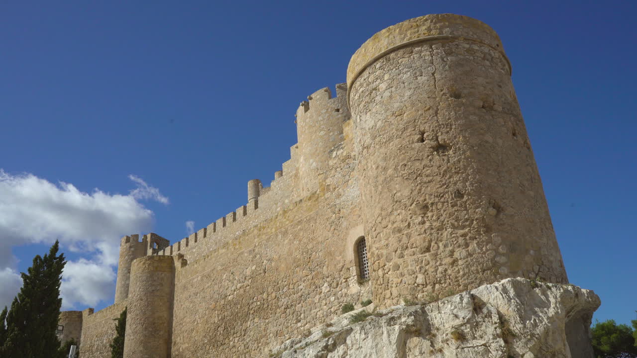 Low angle time-lapse view of The Atalaya Castle making incredible view with clouds is moving under the blue sky, Villena, Province of Alicante, southern Spain.