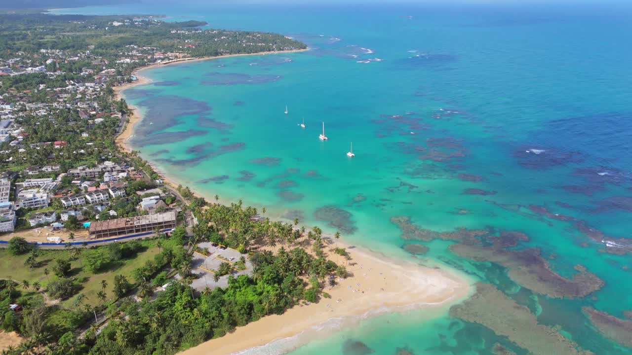 Aerial establishing shot of Punta Popy Beach in Las terrenas, Samana, Dominican Republic. Coral reef water and coastline of Dominican Republic. Sailing boat on water. Wide shot.