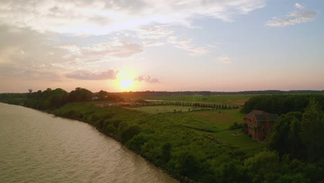 drone backs away from shore and sunset out over the water