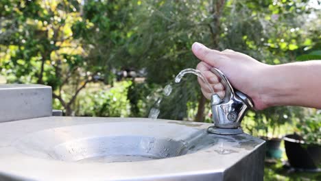 hand pressing a water fountain button repeatedly