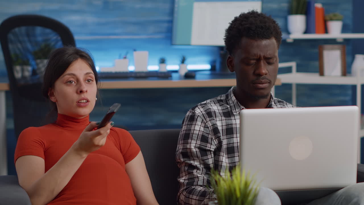 Interracial couple expecting child sitting together on couch