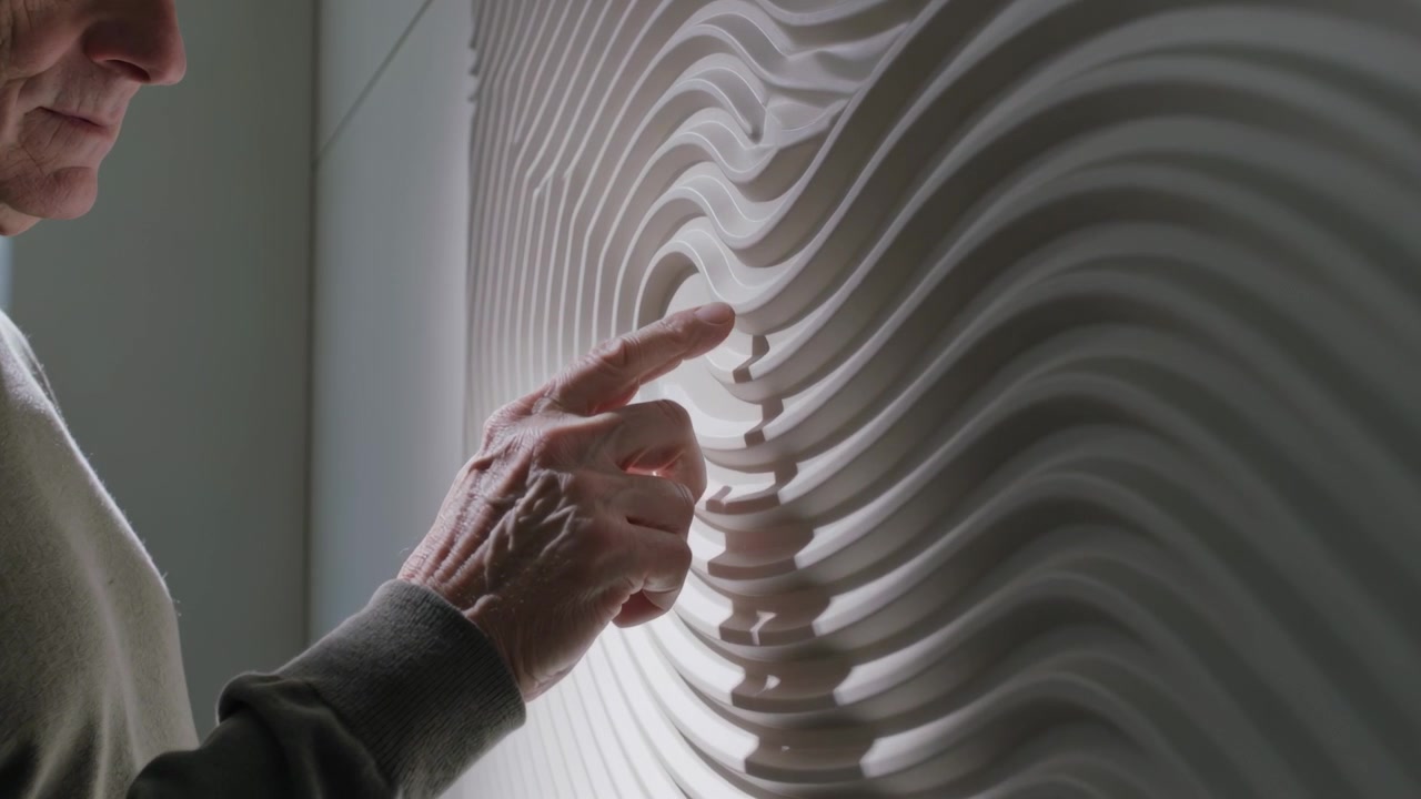 Tracing senior man pressing right index finger near node, examining relief at studio, copy space
