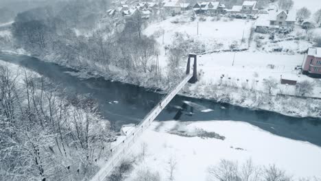 Vista-Aérea-Del-Viejo-Puente-Colgante-Sobre-El-Río-Congelado-En-Una-Mañana-Helada-Y-Nevada