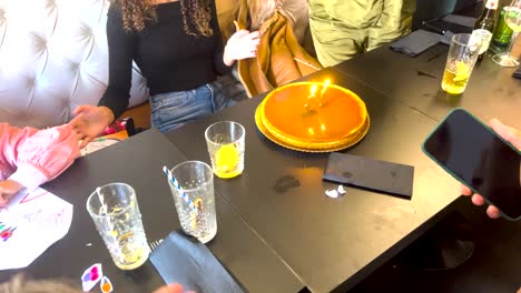 vista cercana de la gente aplaudiendo mientras canta feliz cumpleaños con las velas encendidas en el pastel