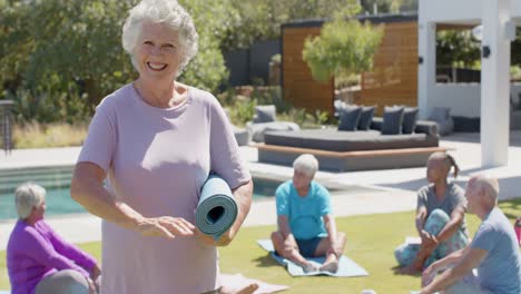 portrait of happy diverse senior woman with yoga group in sunny garden, unaltered, in slow motion