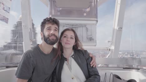 una pareja joven y romántica sentada en una rueda gigante mirando los puntos de referencia y el horizonte de la ciudad, turistas que visitan bruselas