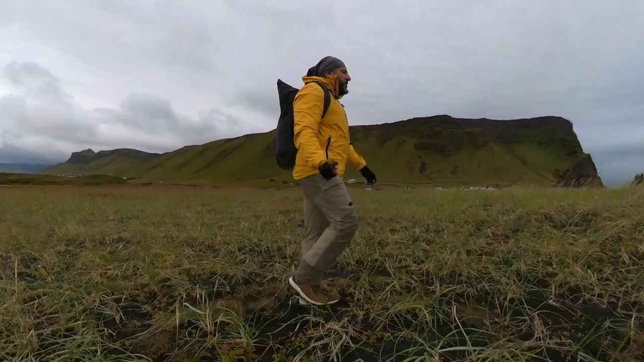 caminando por la hierba de la playa de arena negra de reynisfjara