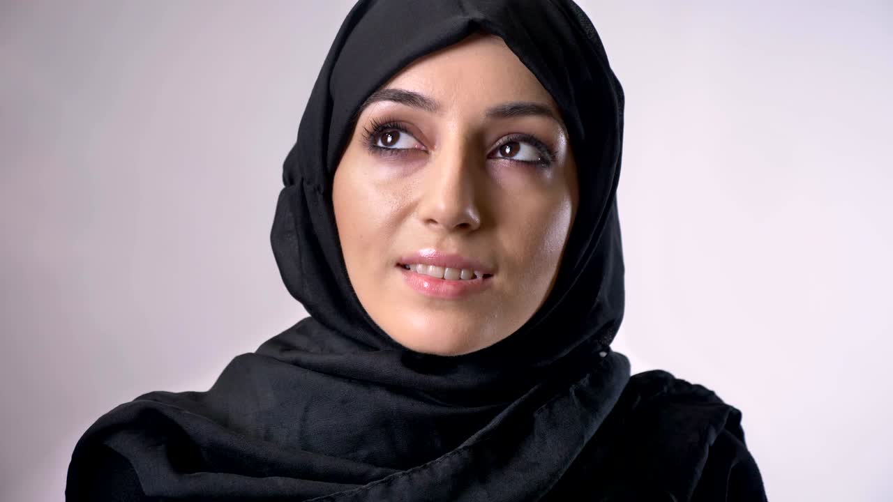 Young sweet muslim girl in hijab is watching at camera, dreaming concept, religious concept, grey background