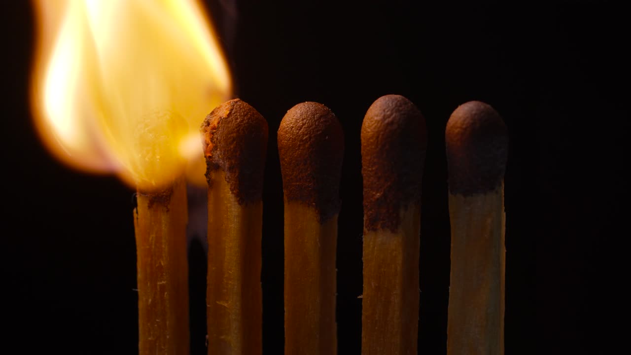 cerca de cinco cabezas de fósforos ardiendo sobre un fondo negro. fósforos de iluminación en cámara lenta. encendido de fuego de 5 fósforos. vista macro.
