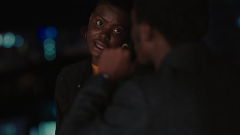 young friends hanging out on rooftop at night chatting having conversation enjoying urban evening african american man flirting with beautiful woman on date