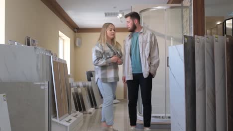a man and a woman are admiring tiles in a building showroom for interior design