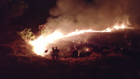 fire extinguisher putting off wild fire at night using shovel