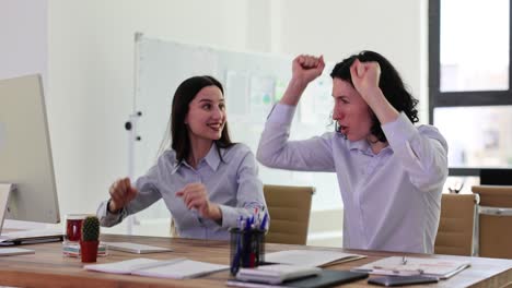 Two women celebrating success in the office