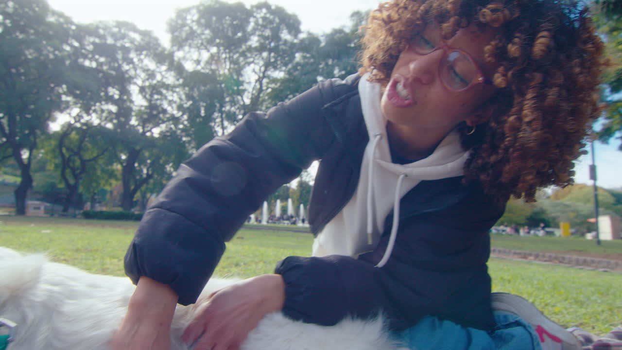 Woman Petting a Dog on Blanket in the Park