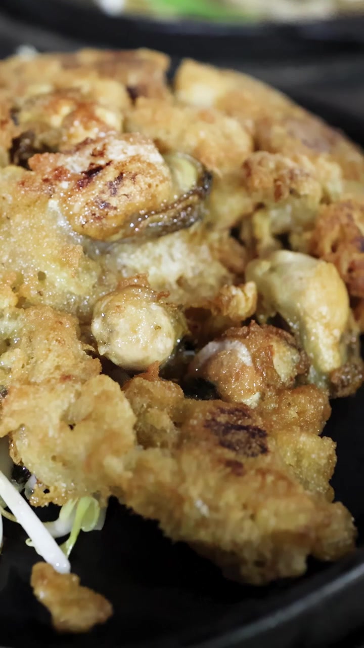 Primo piano di pancake di ostriche fritte dorate su padella calda, vivace scena di street food, messa a fuoco ridotta