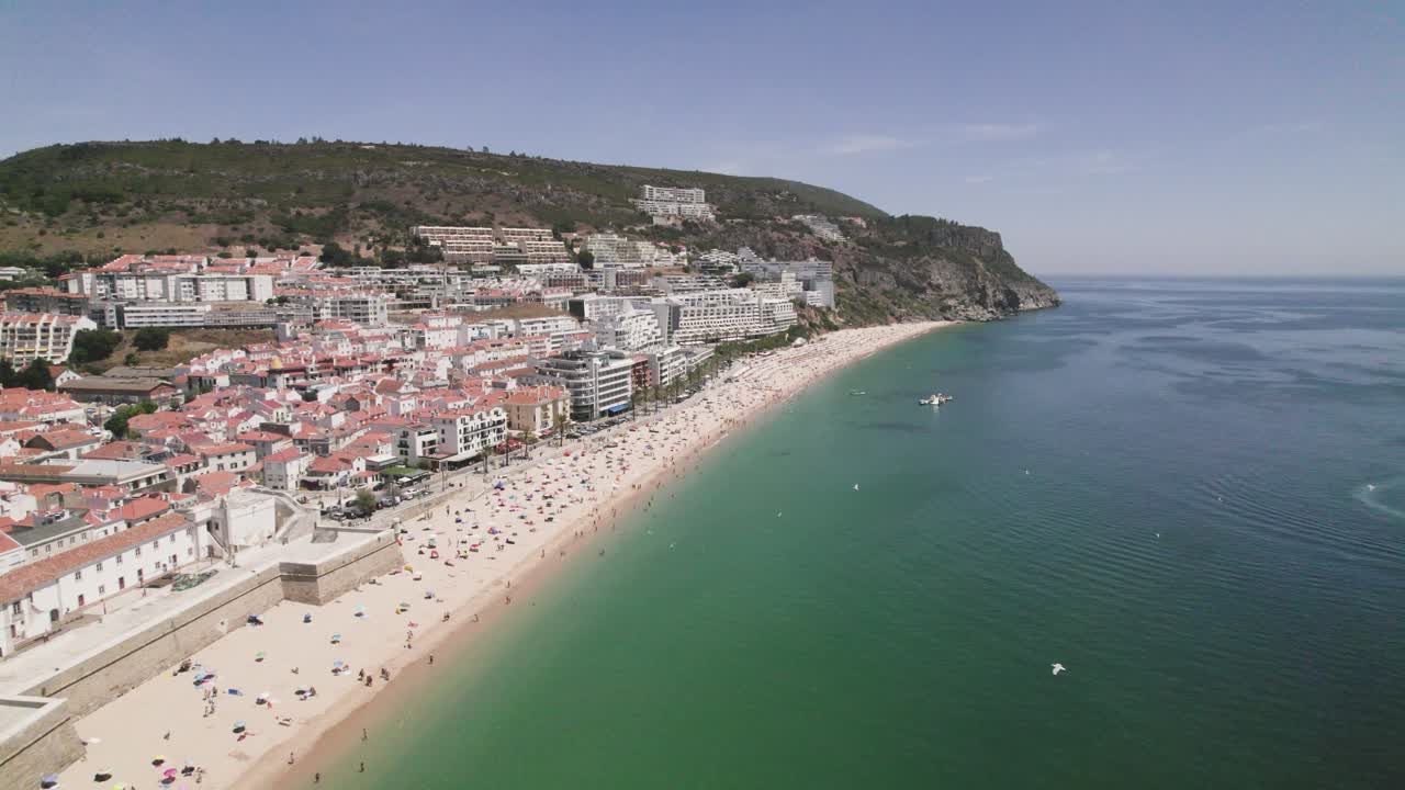 바다 위로 날아가는 갈매기, 세심브라 모래 해변, 언덕을 배경으로 한 도시 풍경