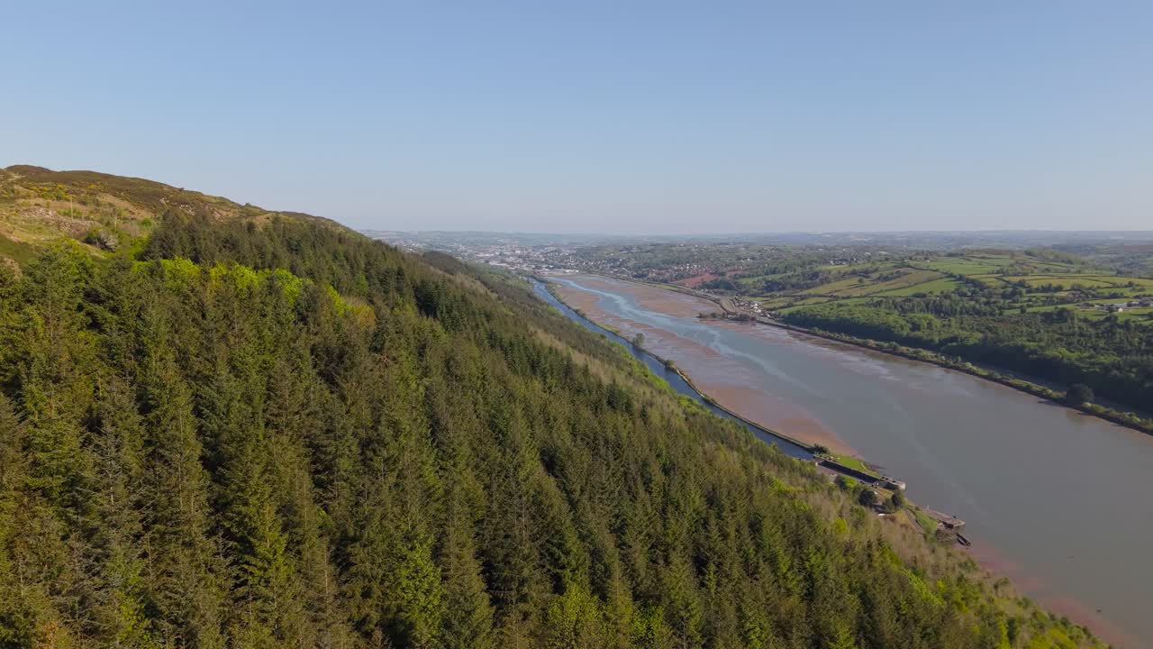 Forested Hillside Next To River On Sunny Day In County Louth Near Dundalk In Ireland. sideways drone shot