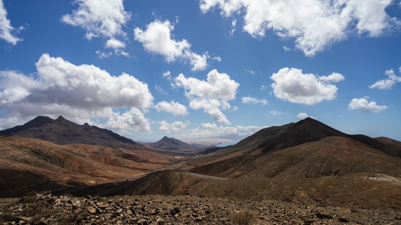 toma de tiempo de nubes hinchadas en el cielo azul sobre el paisaje montañoso yermo - mirador astronomico, fuerteventura