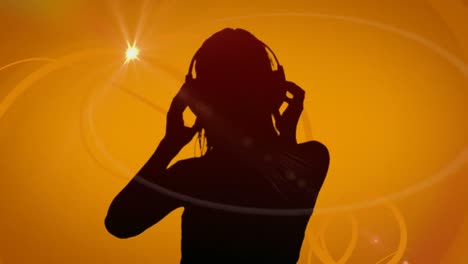 Animation-of-silhouette-of-a-woman-dancing-listening-to-music-with-headphones-on-orange-background