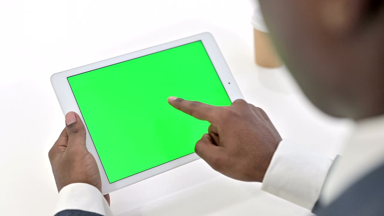 vista trasera de un hombre africano usando una tableta con pantalla de tecla cromada