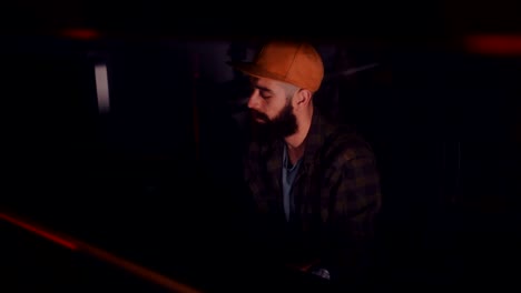 young hipster dj producing music in professional music studio