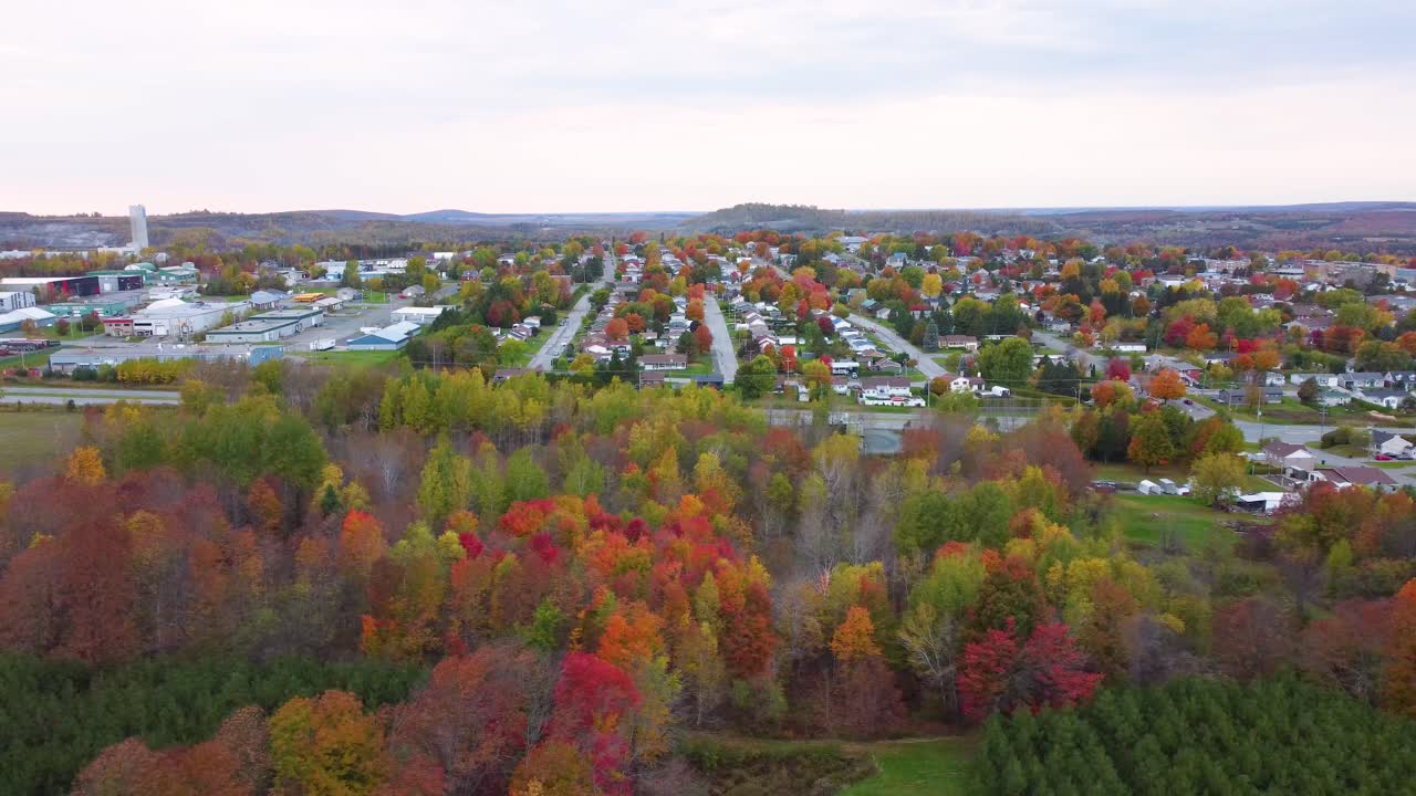 Aerial shot of small village in Estrie, Quebec, Canada during fall with colorful trees and picturesque background