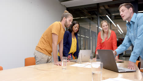 happy diverse colleagues with laptops in discussion at casual office meeting, slow motion