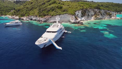 low aerial orbits huge beautiful yacht at shallow ionian sea coast