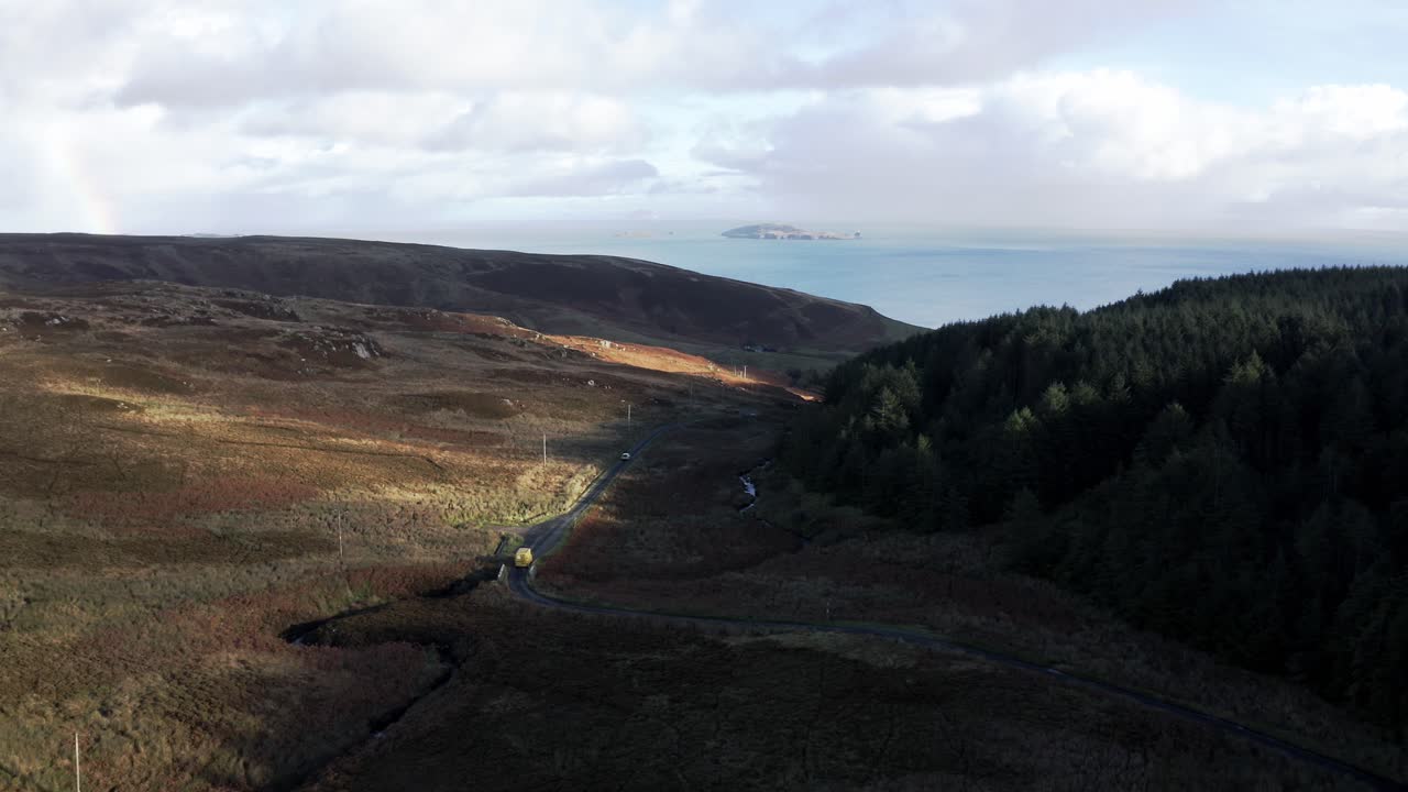 A view of the road cars pass through the wooded and rocky hills of the Mull of Kintyre peninsula in southern Scotland