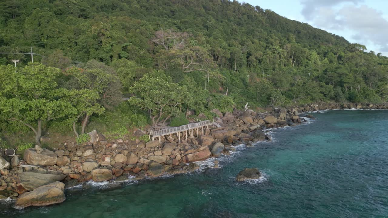 A weathered deck overlooks waves crashing onto a rocky shoreline.