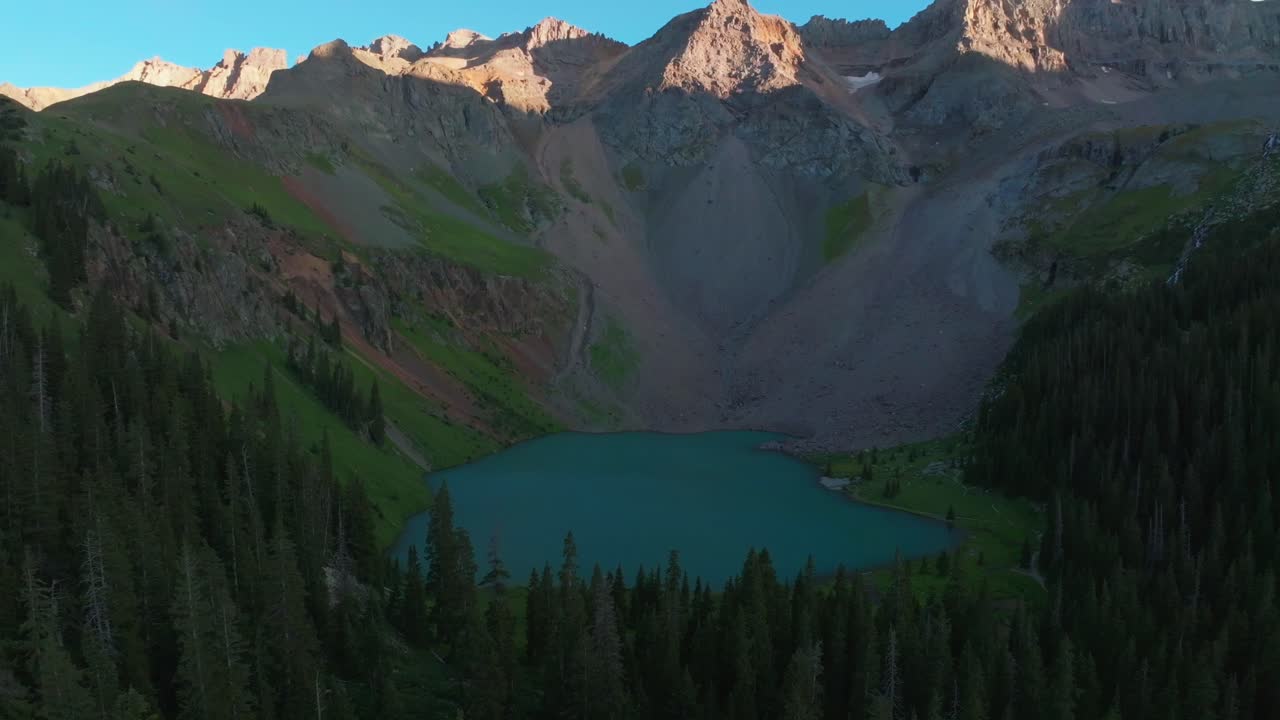 Sunset Lower Blue Lake Mount Sneffels Wilderness Ridgway Telluride Colorado aerial drone golden hour shaded peaks San Juan Rocky Mountains Uncompahgre National Forest last sunlight backward pan motion