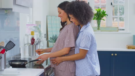 pregnant same sex couple making morning pancakes in kitchen