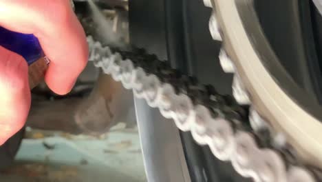primer plano en cámara lenta de rociar la cadena de la moto con lubricante de aceite