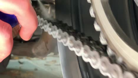 slowmotion closeup of spraying motorbike chain with oil lubricant